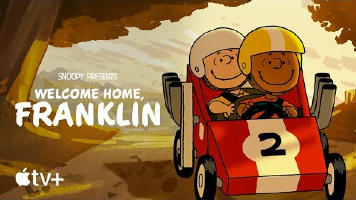 Charlie Brown and Franklin Armstrong ride in a soapbox car through the woods.