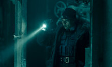 A police officer shines a torch into a dark room.