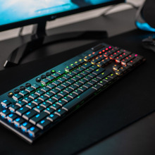 Logitech G915 wireless gaming keyboard on a desk in front of a gaming PC