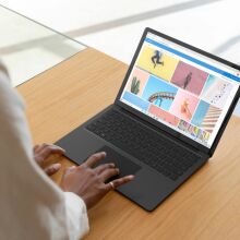 Woman's hand resting on a Microsoft Surface Laptop 3's trackpad, while she sits at a desk