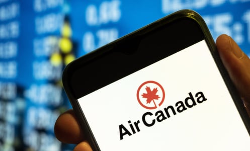 A phone displaying the Air Canada logo in front of a blue departures screen.