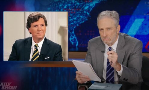 A man sat behind a talk show desk looks sceptical, while another man in a suit is shown in an image top-left.