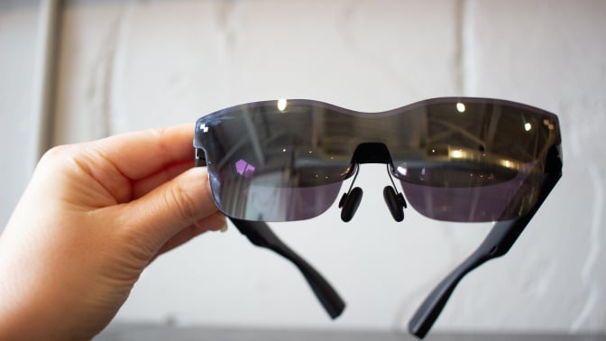 woman's hand holding dark, reflective XR glasses