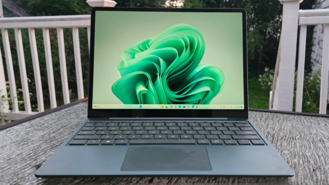 the microsoft surface laptop go 3 on a patio table outside on a deck